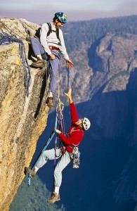 Team of climbers reaching the summit of a rock pinnacle.