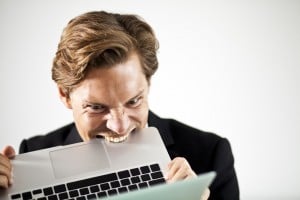 Man biting a laptop in frustration